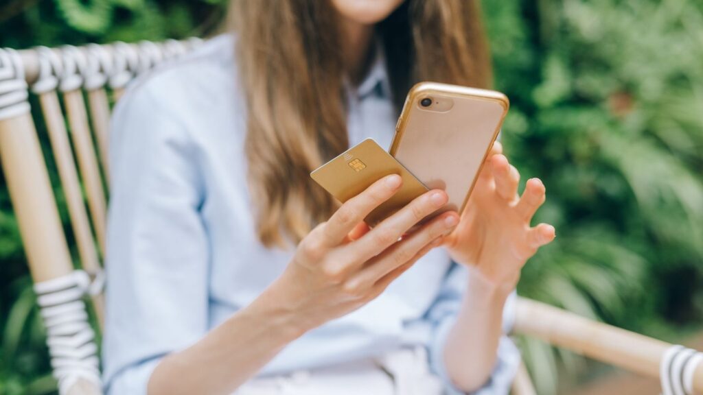 Jugendliche Person mit Smartphone und Bankkarte